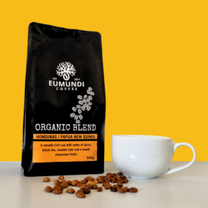 Bag of eumundi coffee organic beans, next to coffee beans and coffee cup